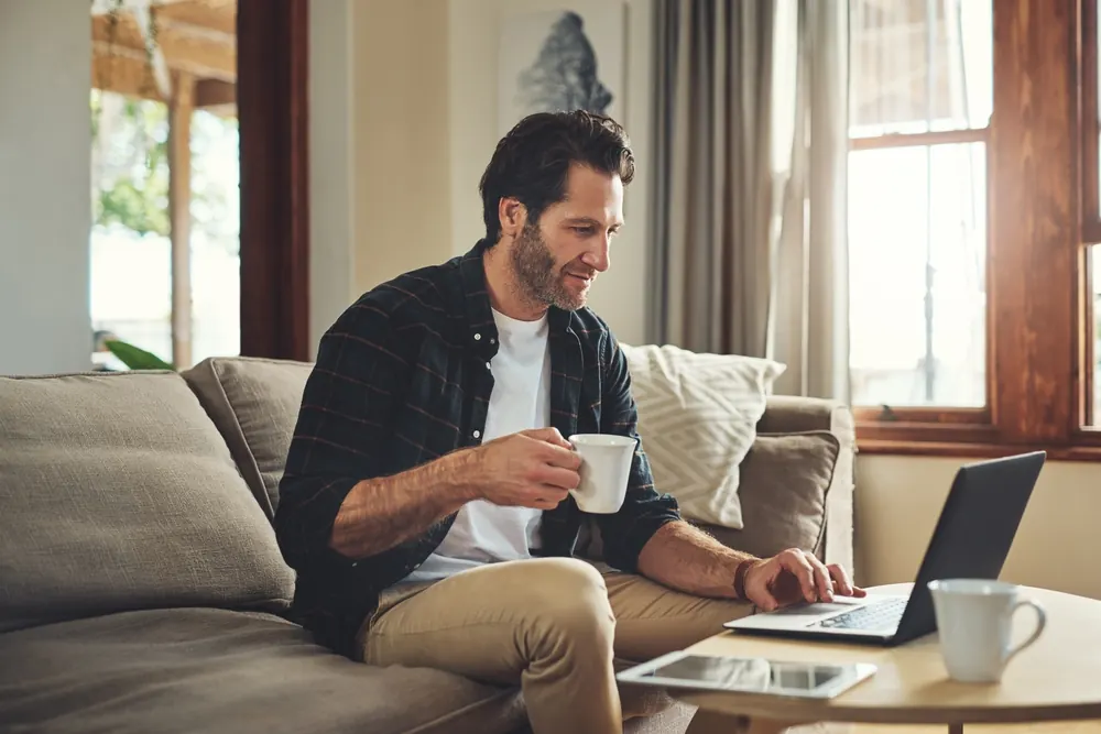 Homeowner relaxing on a sofa with a laptop